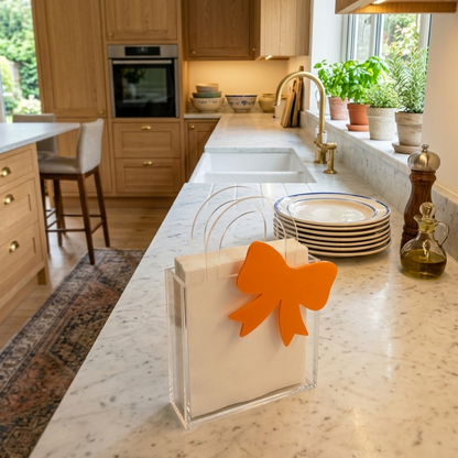 Porta tovaglioli FotoGrafica in acrilico trasparente con decorazione a fiocco arancione su piano cucina in marmo