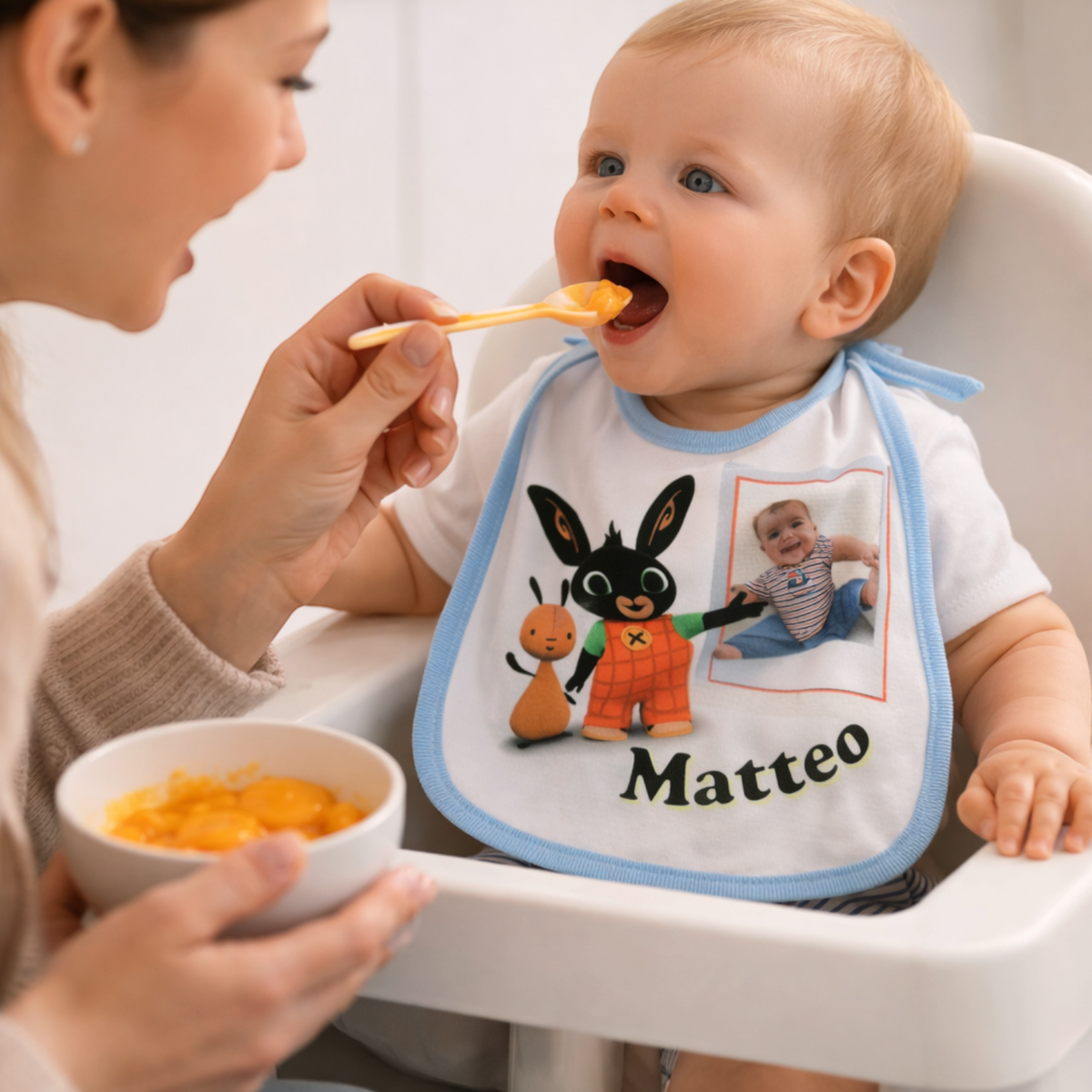 Bavaglino personalizzato FotoGrafica con foto e nome indossato da un bambino che mangia in seggiolone