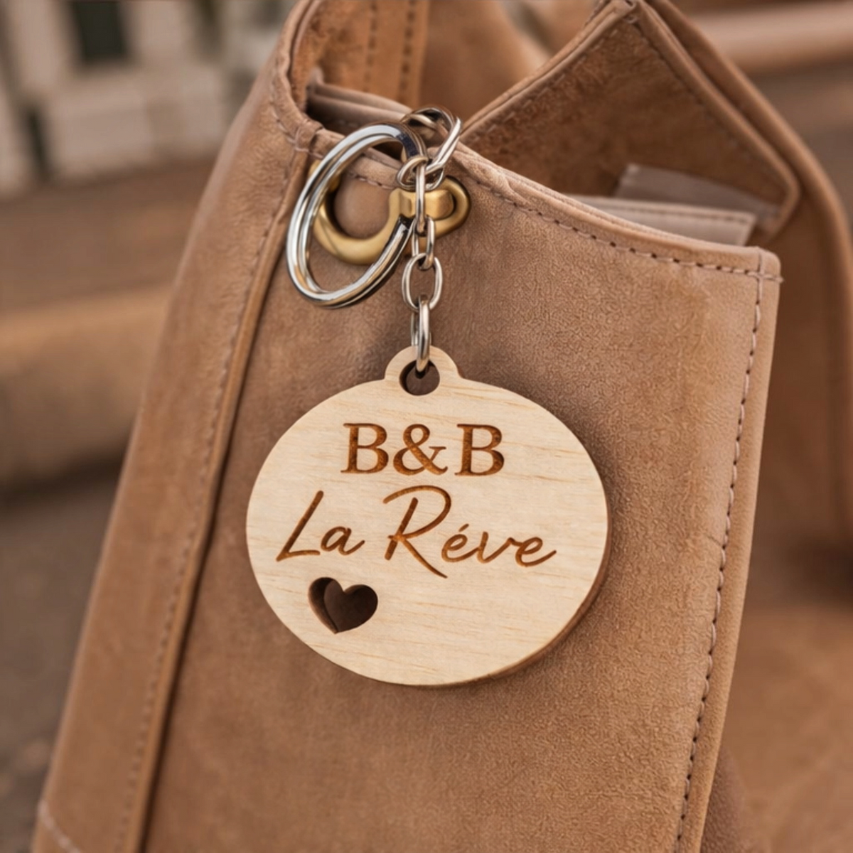Portachiavi personalizzato in legno rotondo con incisione B&B La Réve e cuore, appeso a una borsa FotoGrafica