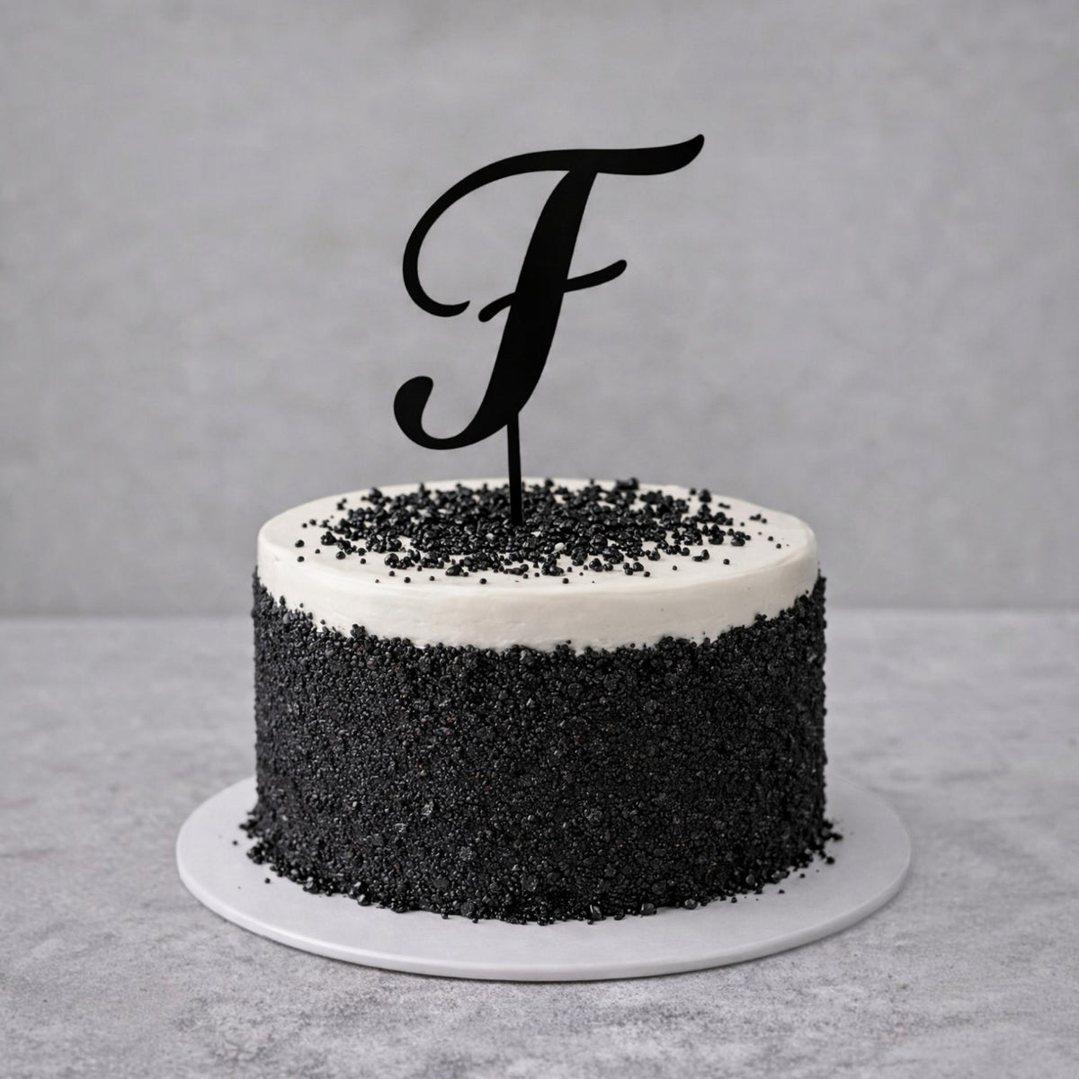 Cake topper personalizzato FotoGrafica con lettera F nera su torta decorata con granella di zucchero nera