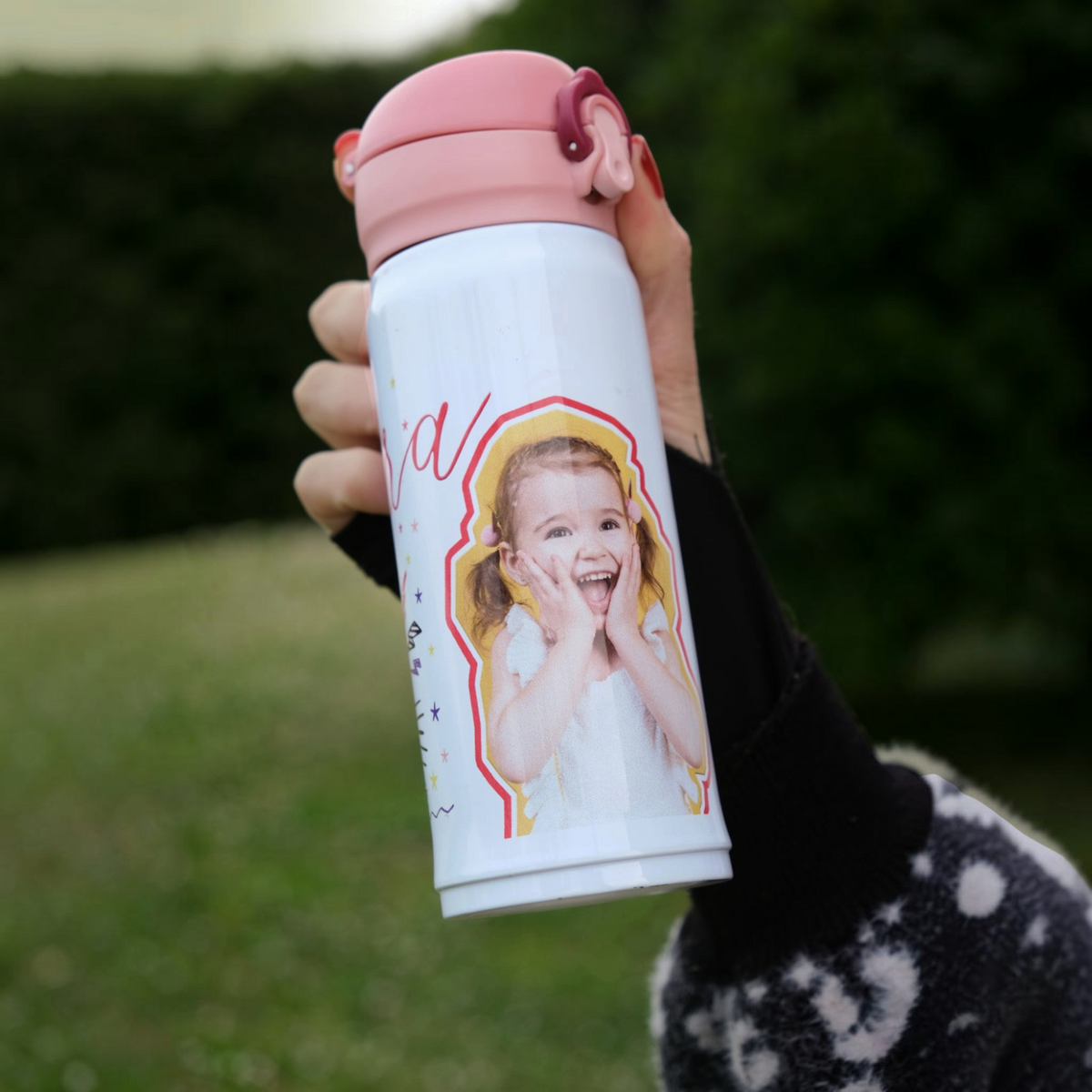 Borraccia FotoGrafica personalizzabile per bambina con foto stampata e tappo rosa, tenuta in mano all'aperto