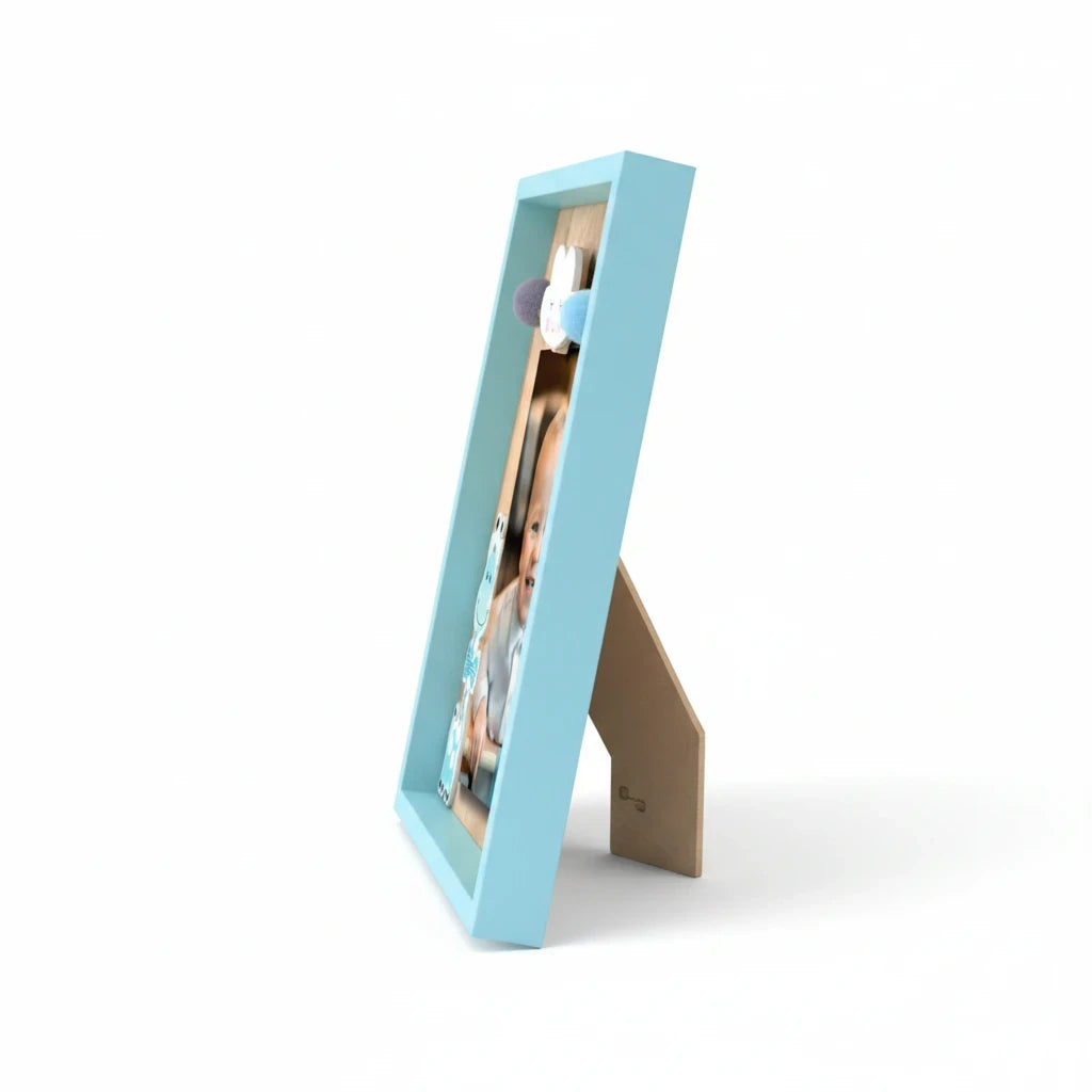 Cornice portafoto FotoGrafica azzurra per neonati con decorazioni in legno e pompon, vista laterale