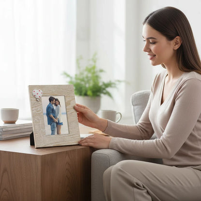 Donna sorridente che tiene una cornice da tavolo FotoGrafica in legno chiaro con decorazione a cuore e scritta Love