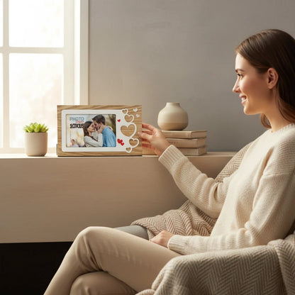 Donna sorridente posiziona una cornice da tavolo FotoGrafica in legno con decorazioni a cuore su un davanzale