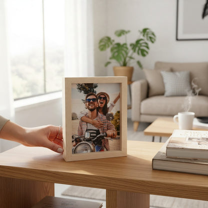 Targa cornice FotoGrafica in legno chiaro con foto di coppia in moto, posizionata su un tavolo in un soggiorno moderno